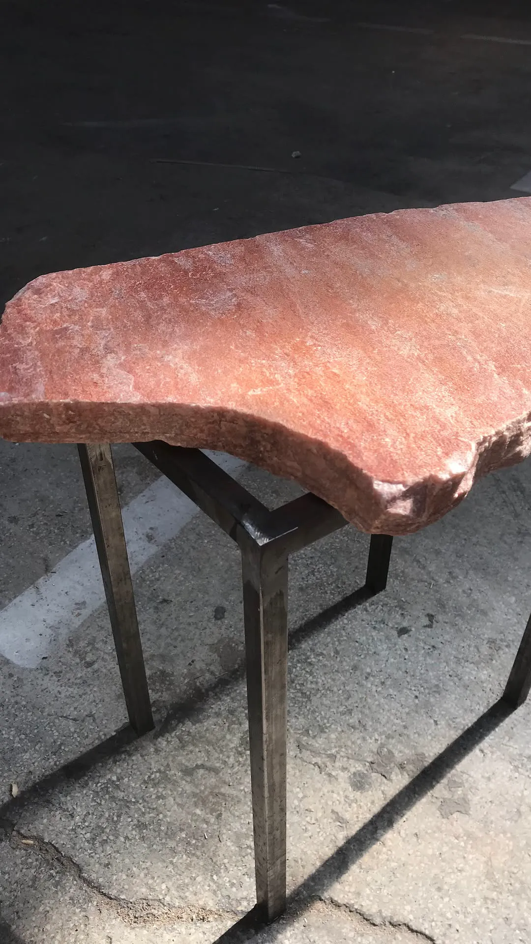 Pièce de mobilier à plateau rouge et piètement métallique, présentée dans la rue